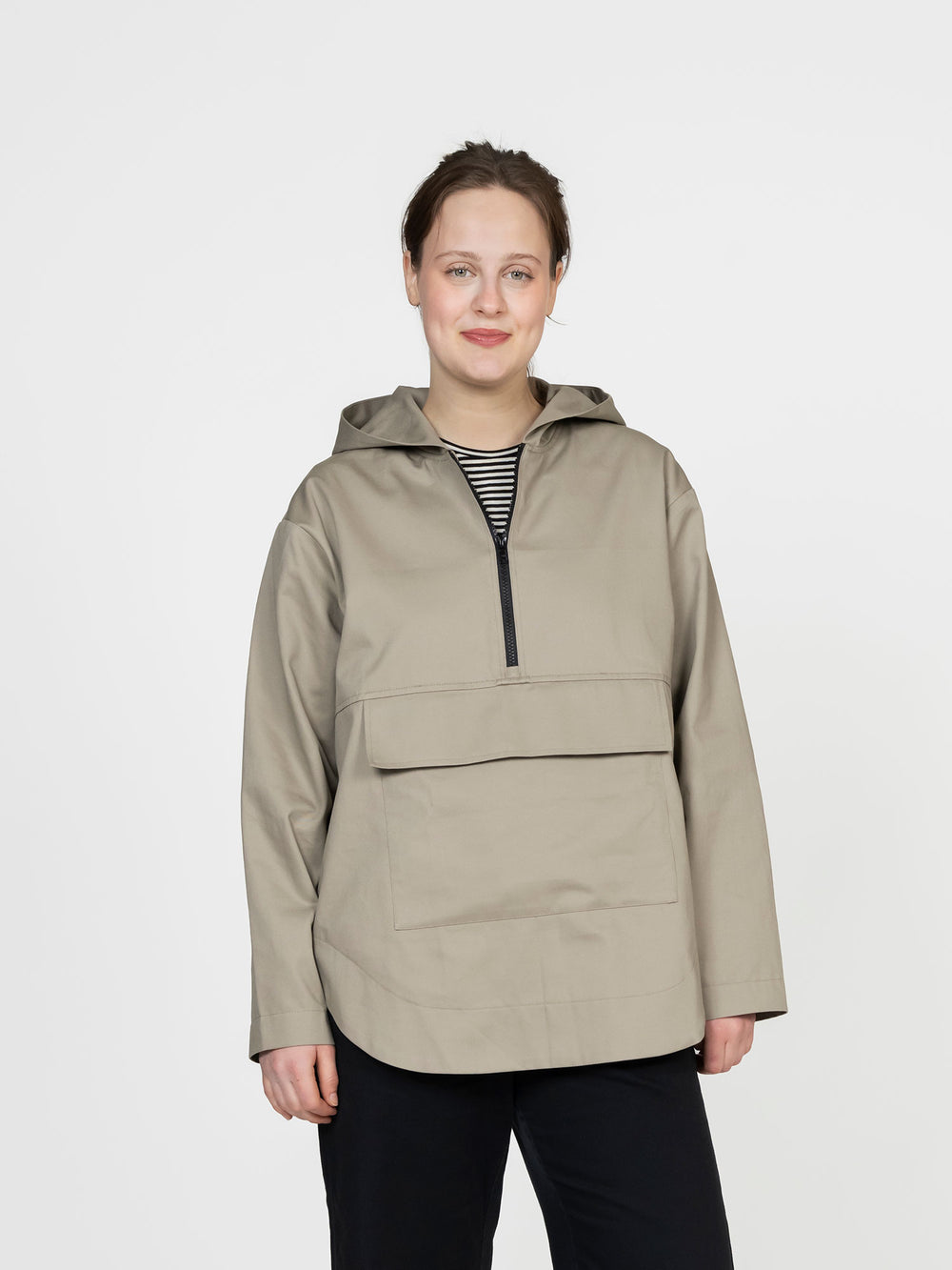 Woman wearing the Anorak sewing pattern from The Assembly Line on The Fold Line. A jacket pattern made in light to medium weight fabric, featuring a hood, short front zipper opening, and large front patch pocket with a flap.
