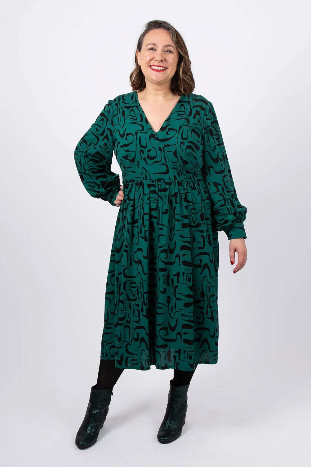 Woman wearing the Antonia Dress sewing pattern from Sew Over It on The Fold Line. A dress pattern made in viscose, crepe, gingham, or velvet fabric, featuring a deep V-neckline, tea dress style lined bodice, long sleeves with cuffs, gathered skirt, and midi length.