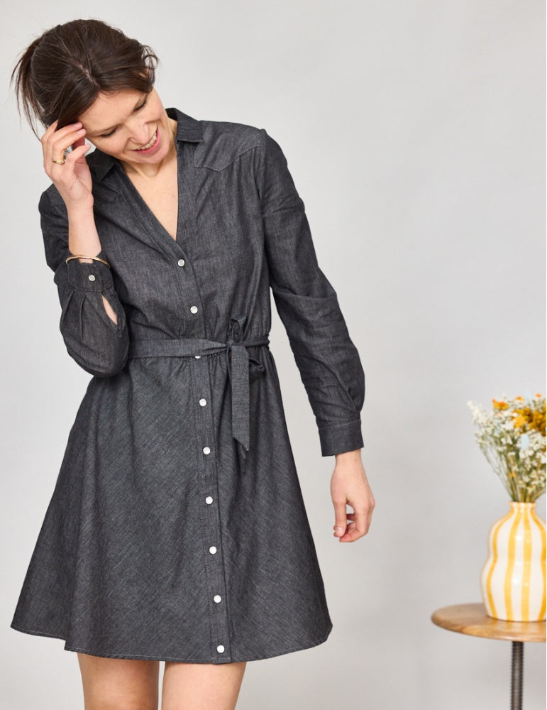Woman wearing the Arizona Dress sewing pattern from Atelier Scämmit on The Fold Line. A dress pattern made in cotton, linen, or viscose fabric, featuring a shirt collar, V-neck, shoulder yokes, button front, long sleeves with cuffs, and mini length.