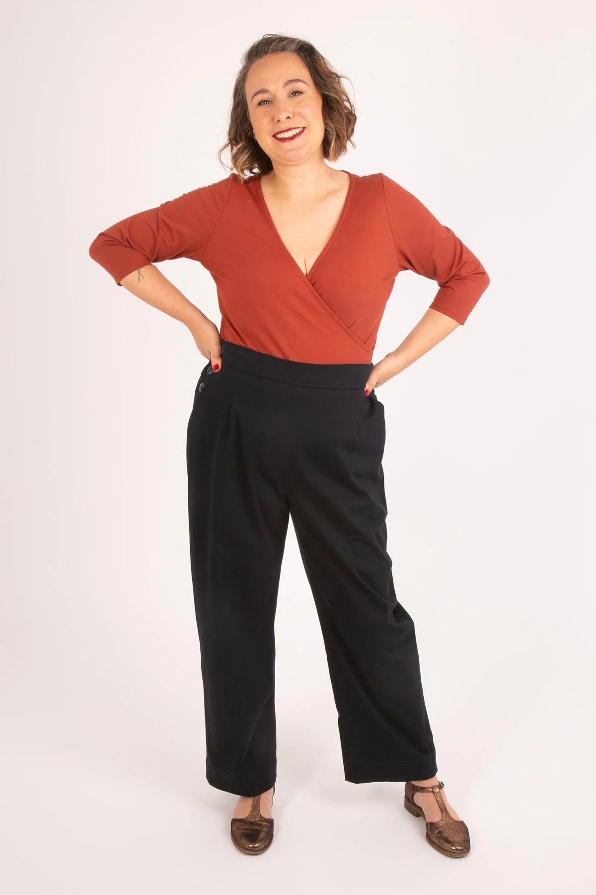 Woman wearing the Astrid Bodysuit sewing pattern from Sew Over It on The Fold Line. A bodysuit pattern made in cotton jersey fabric, featuring a faux wrap front, deep V-neckline, 3/4 length sleeves, and a lined gusset with popper fastenings.
