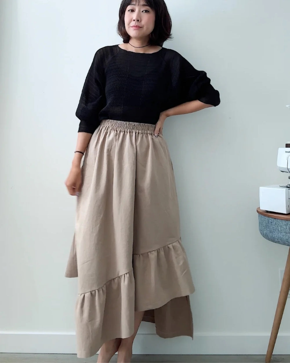 Woman wearing the Asymmetric Ruffle Skirt sewing pattern from Sewing Therapy on The Fold Line. A skirt pattern made in viscose/rayon, tencel/lyocell twill, double gauze, washed lightweight linen, lightweight chambray or slub cotton, drapey wool blends or fine wool flannel, or babycord fabric, featuring an A-line silhouette, elastic waist, pockets, and asymmetric ruffle hem.