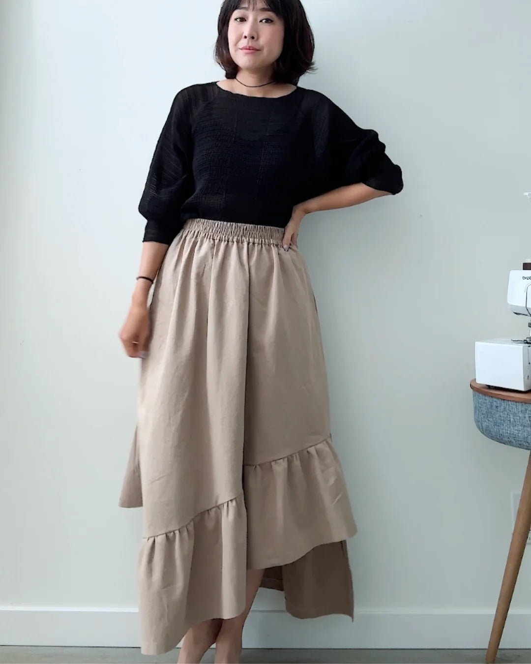 Woman wearing the Asymmetric Ruffle Skirt sewing pattern from Sewing Therapy on The Fold Line. A skirt pattern made in viscose/rayon, tencel/lyocell twill, double gauze, washed lightweight linen, lightweight chambray or slub cotton, drapey wool blends or fine wool flannel, or babycord fabric, featuring an A-line silhouette, elastic waist, pockets, and asymmetric ruffle hem.