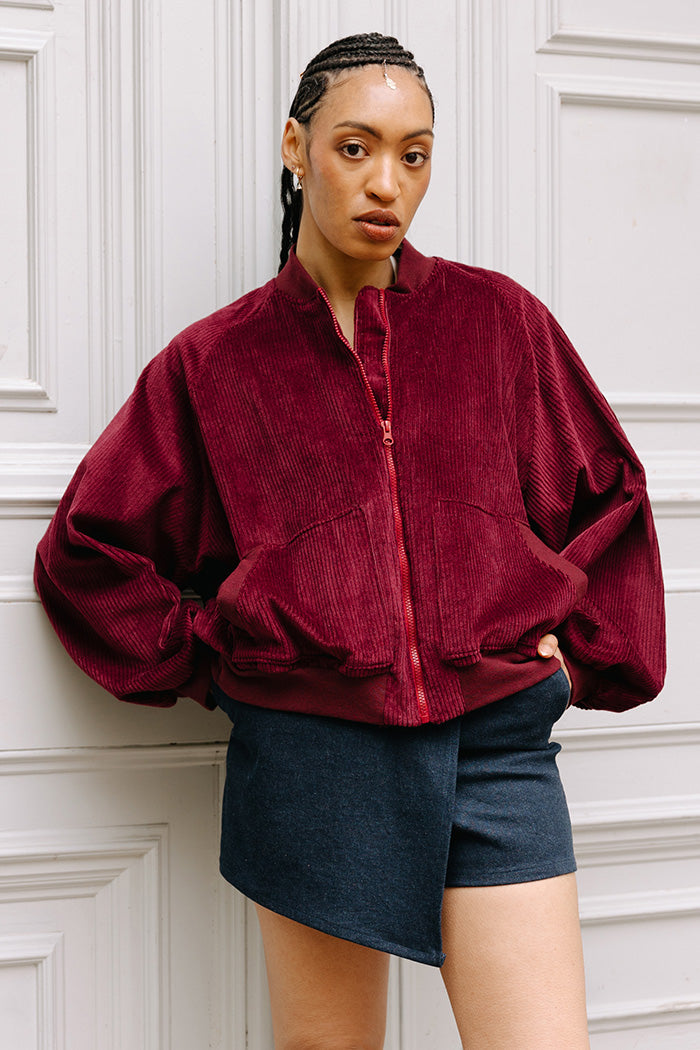 Woman wearing the Audrey Bomber Jacket sewing pattern from JULIANA MARTEJEVS on The Fold Line. A jacket pattern made in corduroy fabric, featuring an oversized fit, wide raglan sleeves, front zipper, patch pockets, and ribbed trim. 