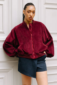 Woman wearing the Audrey Bomber Jacket sewing pattern from JULIANA MARTEJEVS on The Fold Line. A jacket pattern made in corduroy fabric, featuring an oversized fit, wide raglan sleeves, front zipper, patch pockets, and ribbed trim. 