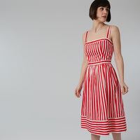Woman wearing the Aurélie Dress sewing pattern from Coralie Bijasson on The Fold Line. A sundress pattern made in viscose crepe, linen, or cotton fabric, featuring a fitted bodice with thin straps and a gathered mid-calf length skirt. 