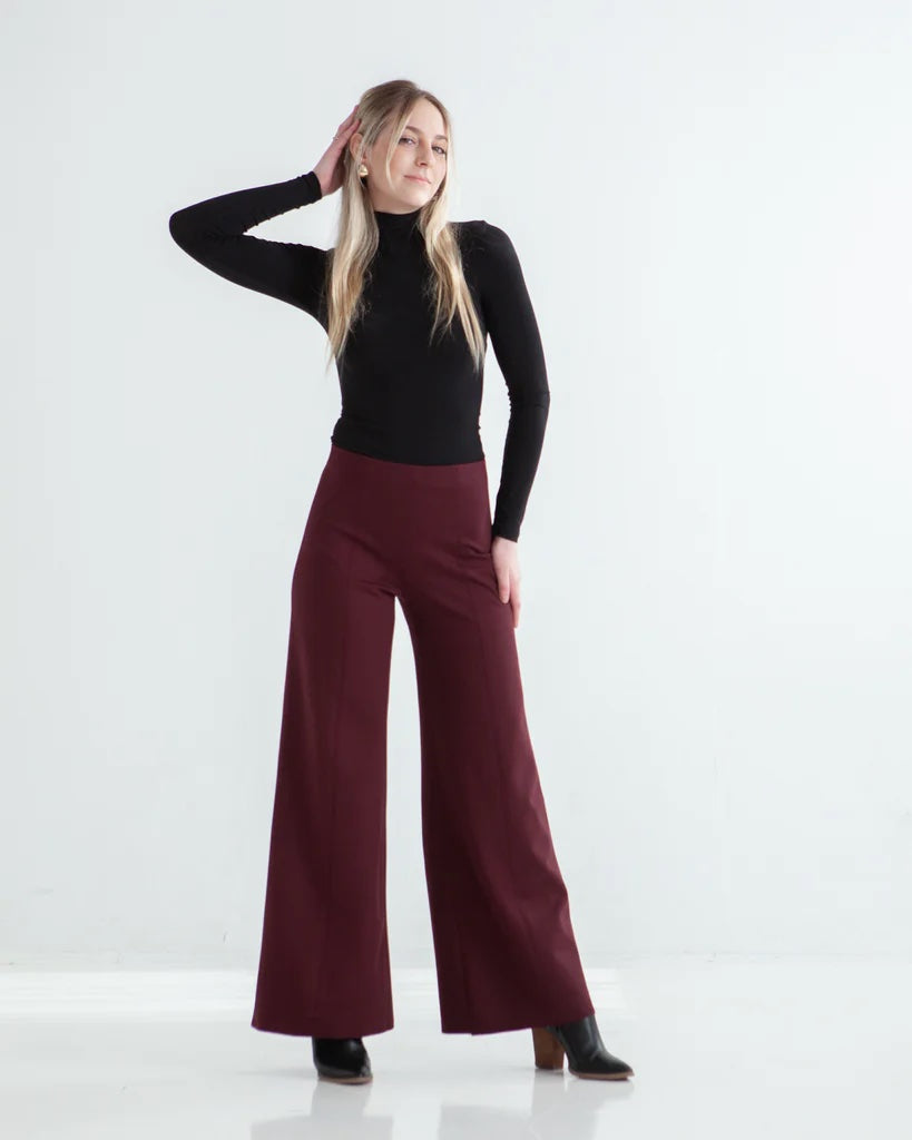 Woman wearing the Ayla Pant sewing pattern from True Bias on The Fold Line. A trousers pattern made in ponte, double knit, french terry, knit jacquard, or sweater knit fabric, featuring an elastic waistband, fitted waist and hips, and wide legs.