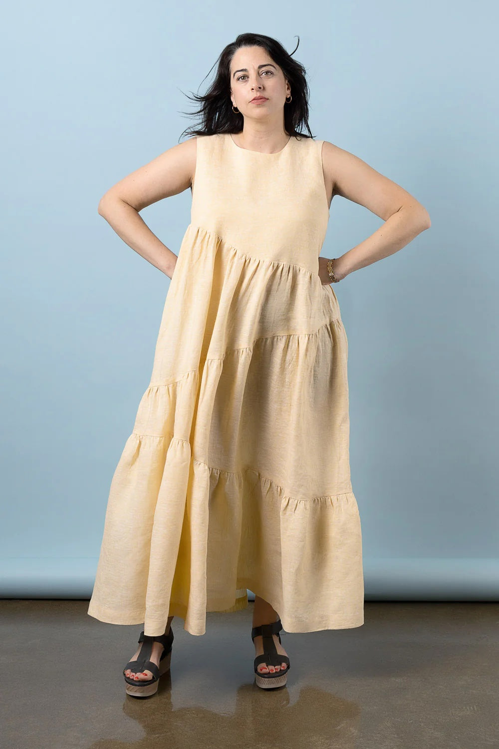 Woman wearing the Azure Dress sewing pattern from Closet Core Patterns on The Fold Line. A sleeveless dress pattern made in linen, cotton poplin, voile, chambray, double gauze, batiste, shirting, rayon challis, viscose, tencel twill, or silk crepe de chine fabric, featuring a round neckline, three diagonal gathered tiers, and maxi length.