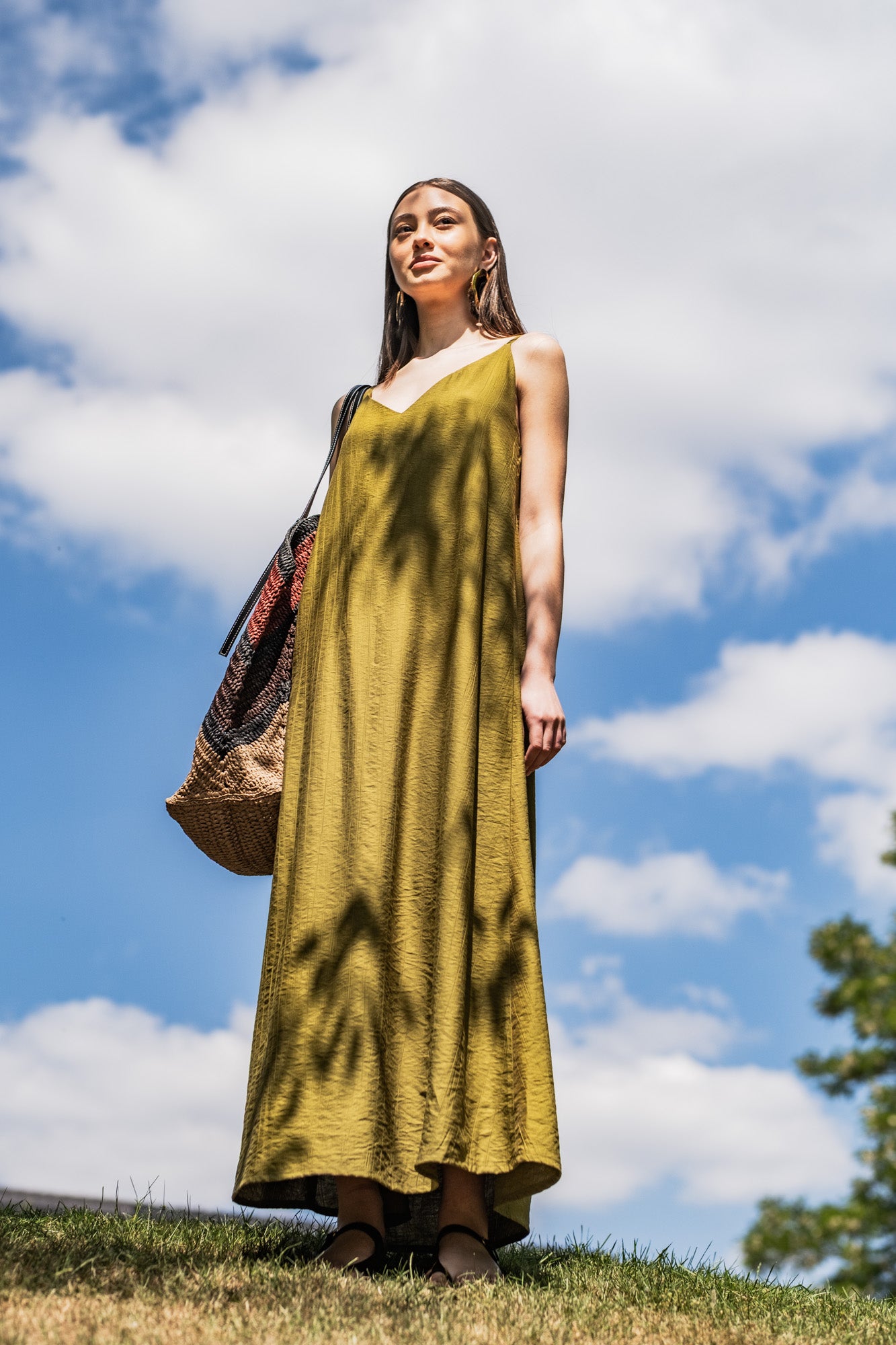 Woman wearing the Azure Dress sewing pattern from Fibre Mood on The Fold Line. A slip dress pattern made in drapey, crinkle jacquard, poplin, seersucker, or dobby fabric, featuring a deep V-neckline, thin straps, and maxi length.