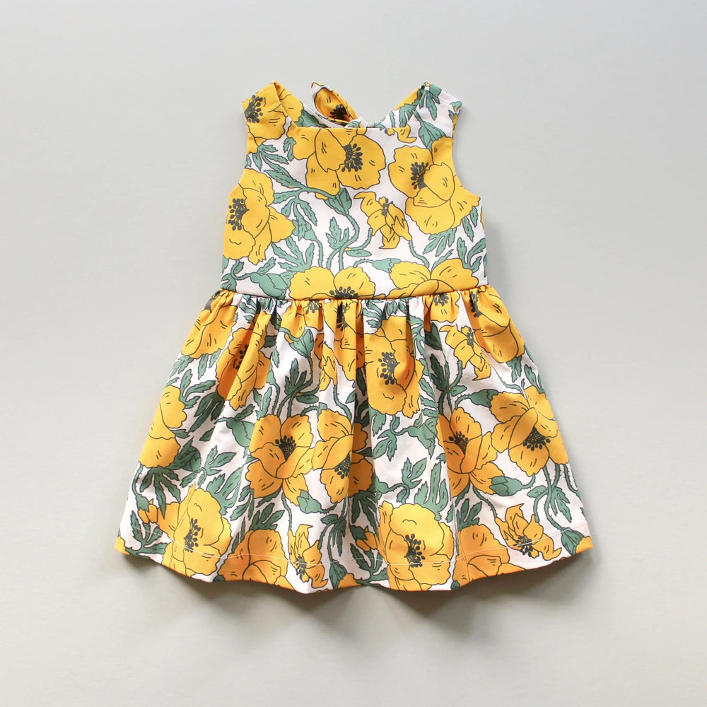 The Baby/Child Daisy Dress sewing pattern from Oh Me Oh My Sewing on The Fold Line. A dress pattern made in quilting cotton, washed linen, double gauze, cotton lawn, voile, or rayon challis fabric, featuring a square neckline, lined bodice, tie back with elastic, and full gathered skirt. 