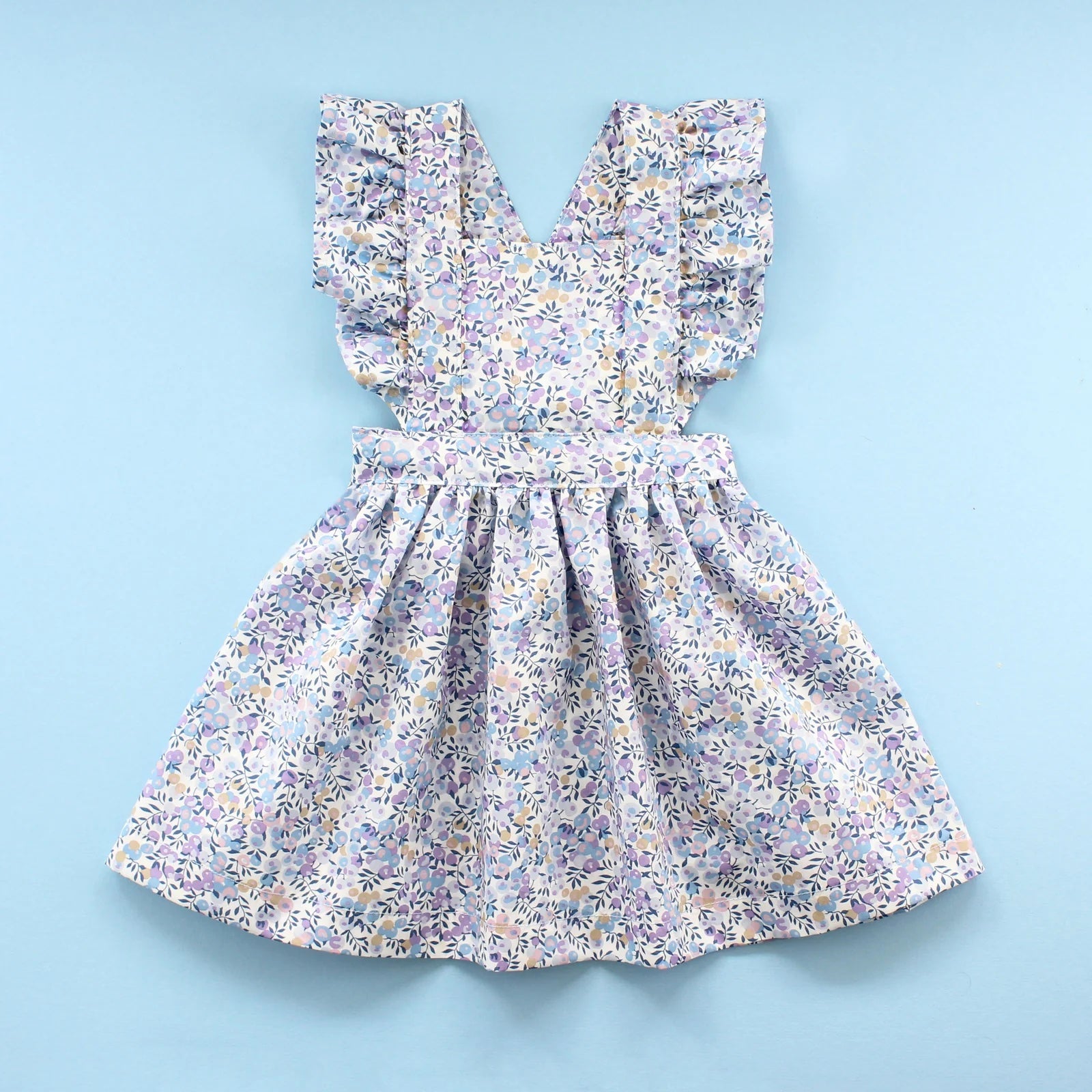 The Baby/Child Flutter Pinafore Dress sewing pattern from Oh Me Oh My Sewing on The Fold Line. A dress pattern made in quilting cotton, washed linen, double gauze, cotton lawn, voile, or rayon challis fabric, featuring a bib with ruffled straps and a full gathered skirt.
