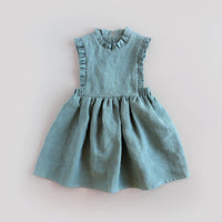 The Baby/Child Lily of the Valley Pinafore sewing pattern from Oh Me Oh My Sewing on The Fold Line. A pinafore dress pattern made in quilting cotton, washed linen, double gauze, cotton lawn, voile, or rayon challis fabric, featuring a bib bodice with ruffles, full gathered skirt, elastic at the sides, and keyhole closure at the back.