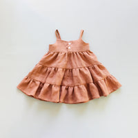 The Baby/Child Magnolia Dress sewing pattern from Oh Me Oh My Sewing on The Fold Line. A dress pattern made in quilting cotton, washed linen, double gauze, cotton lawn, voile, or rayon challis fabric, featuring a button up bodice, thin straps, and tiered skirt.