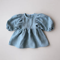 The Baby/Child Maisie Dress sewing pattern from Oh Me Oh My Sewing on The Fold Line. A dress pattern made in quilting cotton, washed linen, double gauze, cotton lawn, voile, or rayon challis fabric, featuring a round neckline, puff sleeves, and gathered skirt.