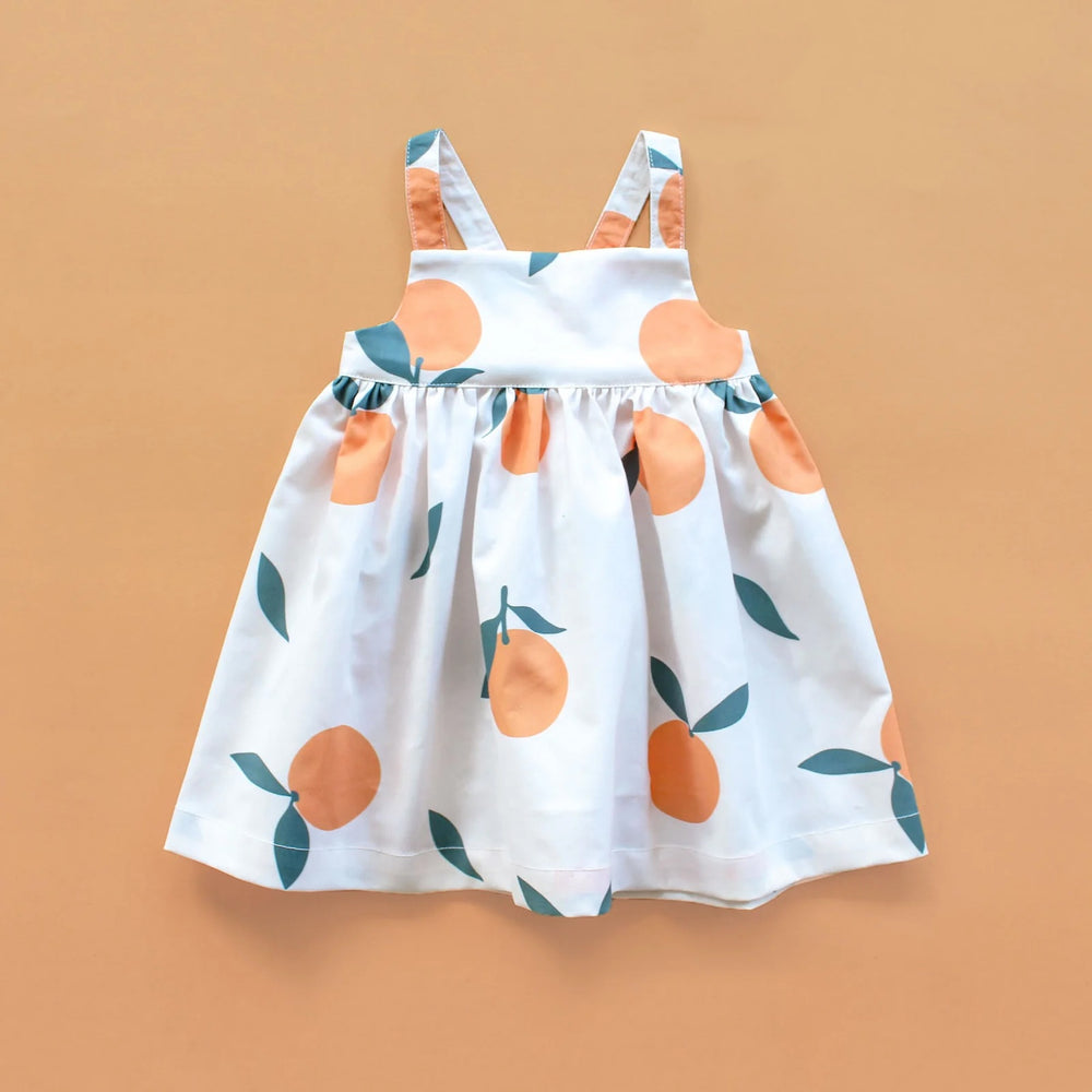The Baby/Child Marigold Dress sewing pattern from Oh Me Oh My Sewing on The Fold Line. A dress pattern made in quilting cotton, washed linen, double gauze, cotton lawn, voile, or rayon challis fabric, featuring a square neckline, empire waist, elastic back, adjustable straps, and full gathered skirt.