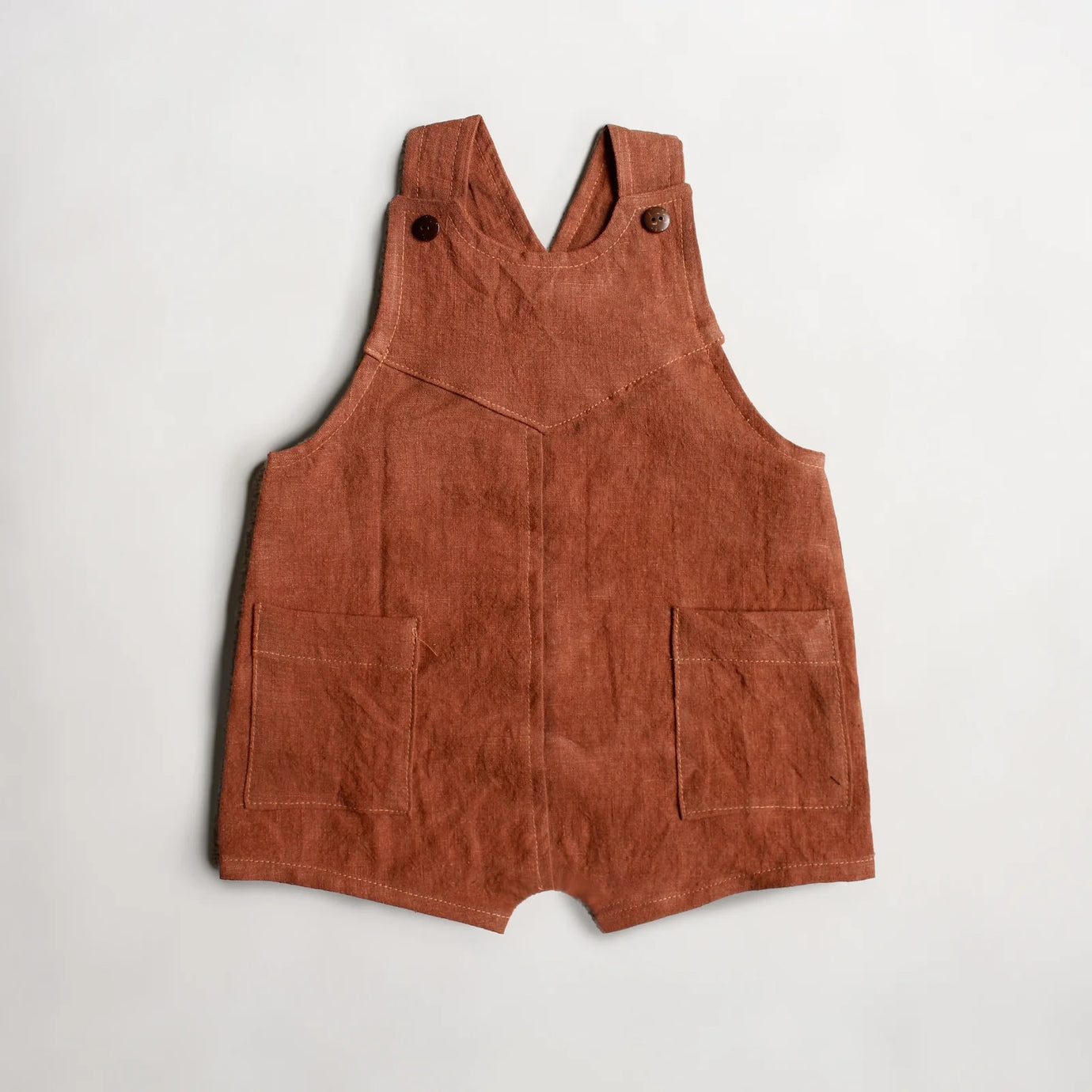 The Baby/Child Orion Overalls sewing pattern from Oh Me Oh My Sewing on The Fold Line. A dungarees pattern made in quilting cotton, washed linen, double gauze, or cotton lawn fabric, featuring an oversized fit, unique yoke detail, adjustable straps, patch pockets, and shorts length.