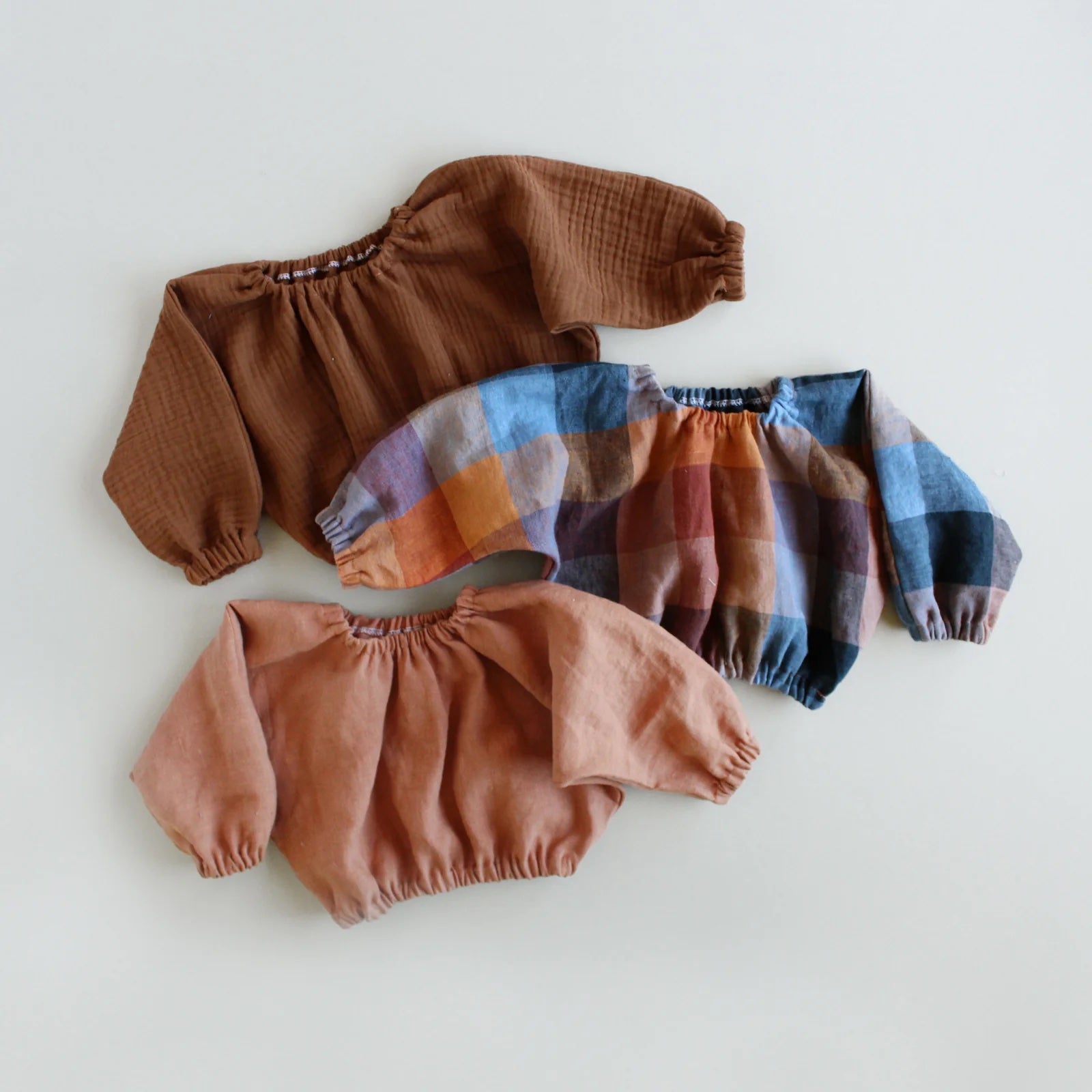 The Baby/Child Sola Top sewing pattern from Oh Me Oh My Sewing on The Fold Line. A top pattern made in voile, rayon, washed linen, double gauze, or sandwashed cotton fabric, featuring an oversized fit, grown-on sleeves, elastic neckline, elastic hem, and elastic sleeve hems.