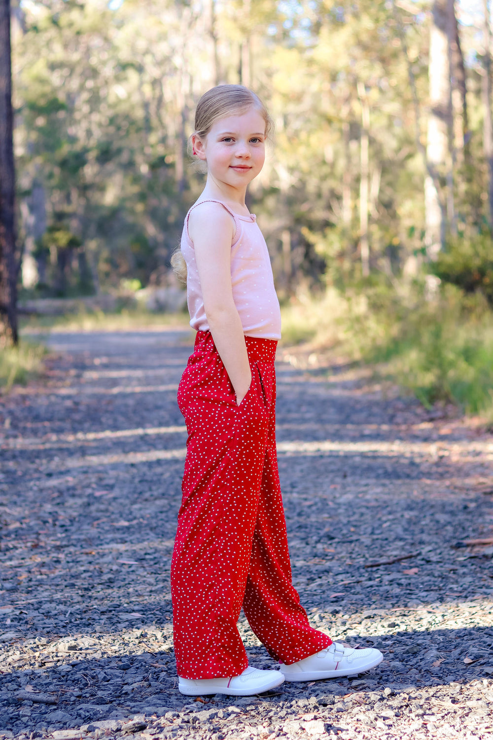 Girl wearing the Baby/Child Waratah Wide Leg Pants sewing pattern from Waves & Wild on The Fold Line. A pants pattern made in viscose, rayon, silk, poplin, lawn, linen blend, or chambray fabric, featuring an elastic waist with a flat front, front pleats, pockets, and full length legs.