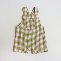 The Baby/Child Woven Overalls sewing pattern from Oh Me Oh My Sewing on The Fold Line. A dungarees pattern made in quilting cotton, lighter canvases, twill, corduroy, or washed linen fabric, featuring a patch pocket, adjustable straps, and shorts length.