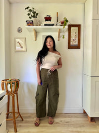 Woman wearing the Baker Barrel Leg Pants sewing pattern from Sew Bake Make on The Fold Line. A trousers pattern made in twill, linen, lightweight canvas, corduroy, or denim fabric, featuring a high rise, elastic waist, drawstring, patch pockets, cargo pockets, and barrel leg.