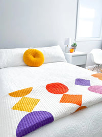 The Beads Quilt sewing pattern from Modern Handcraft on The Fold Line. A quilt pattern made in quilting cotton fabric, featuring circles and diamonds in different colours on a white background.