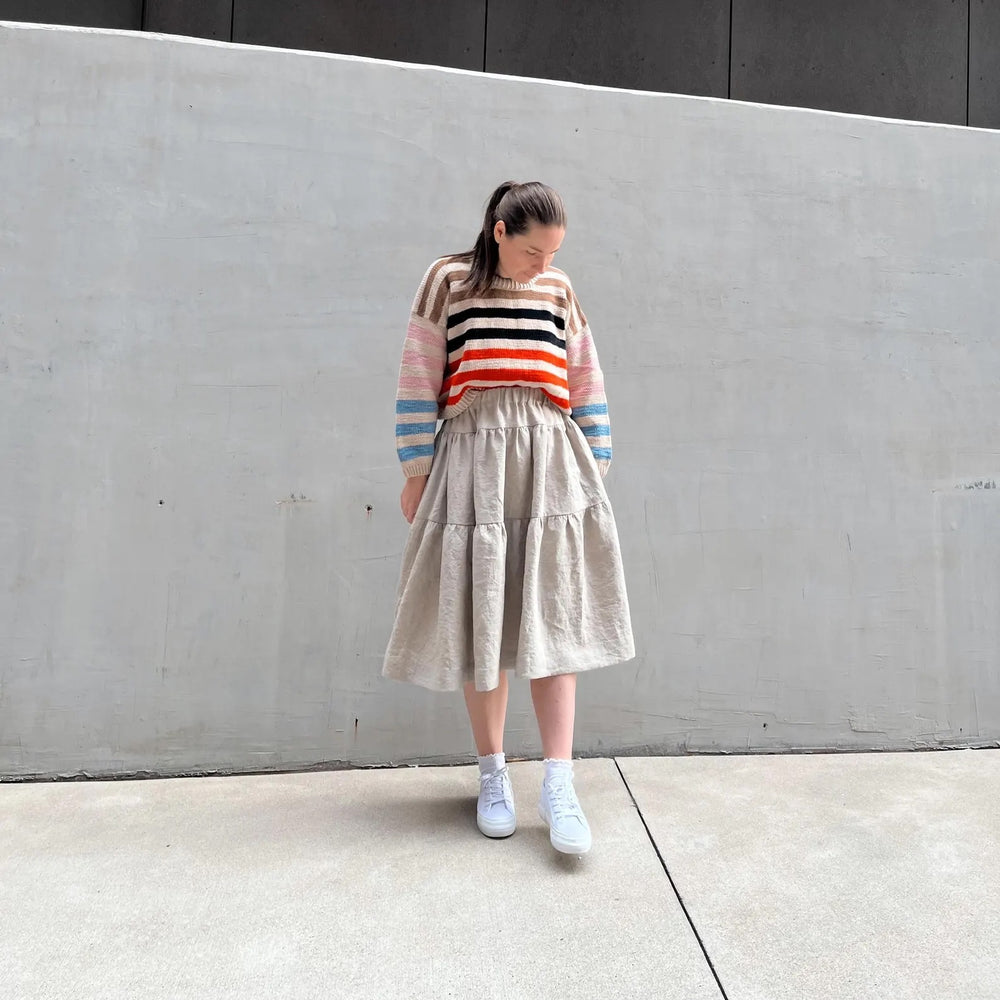 Woman wearing the Bee-Bee Skirt sewing pattern from Me & Kiddo Patterns on The Fold Line. A skirt pattern made in cotton or linen fabric, featuring an elastic waist, gathered tiers, in-seam pockets, and knee length.