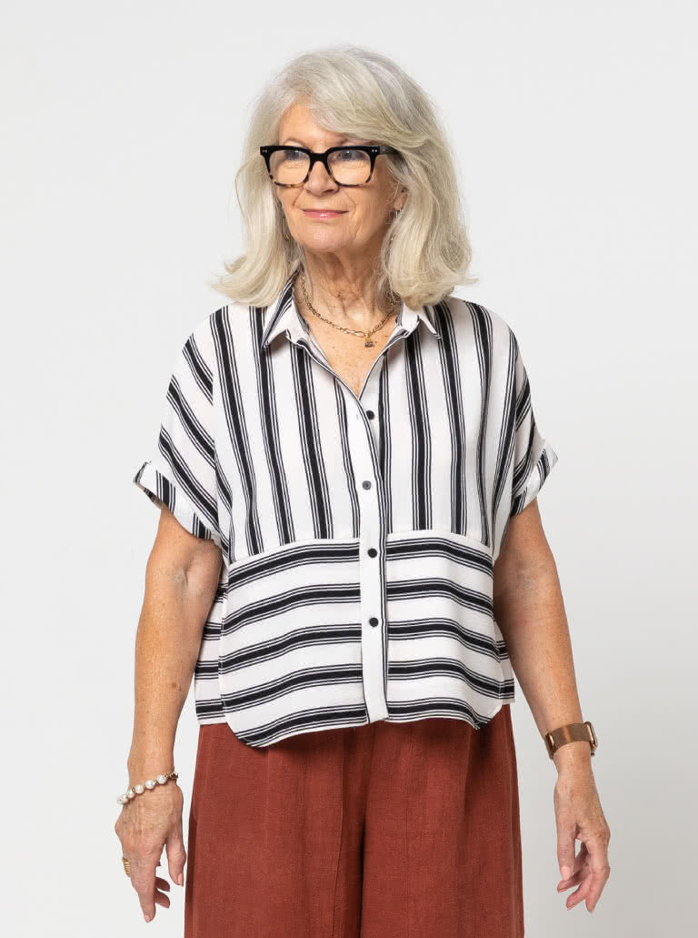 Woman wearing the Blaire Shirt sewing pattern from Style Arc on The Fold Line. A shirt pattern made in washed linen, crepe, chambray, or voile fabric, featuring a small shirt collar, button front, grown-on short sleeves with turn back cuffs, and an overlay.