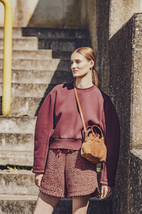 Woman wearing the Boreal Sweater sewing pattern from Fibre Mood on The Fold Line. A sweater pattern made in French terry, interlock jersey, scuba, punto di Roma, double knit, or sweater fabric, featuring a relaxed fit, round neck, long balloon sleeves, and cropped length.