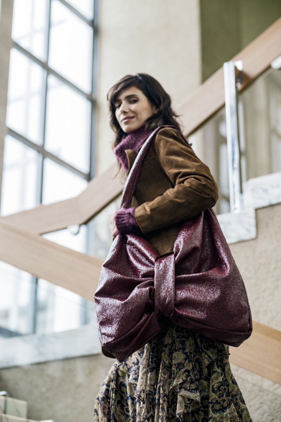 Woman carrying the Bowie Bag sewing pattern from Fibre Mood on The Fold Line. A tote bag pattern featuring a removable central band that creates a bow-like shape.
