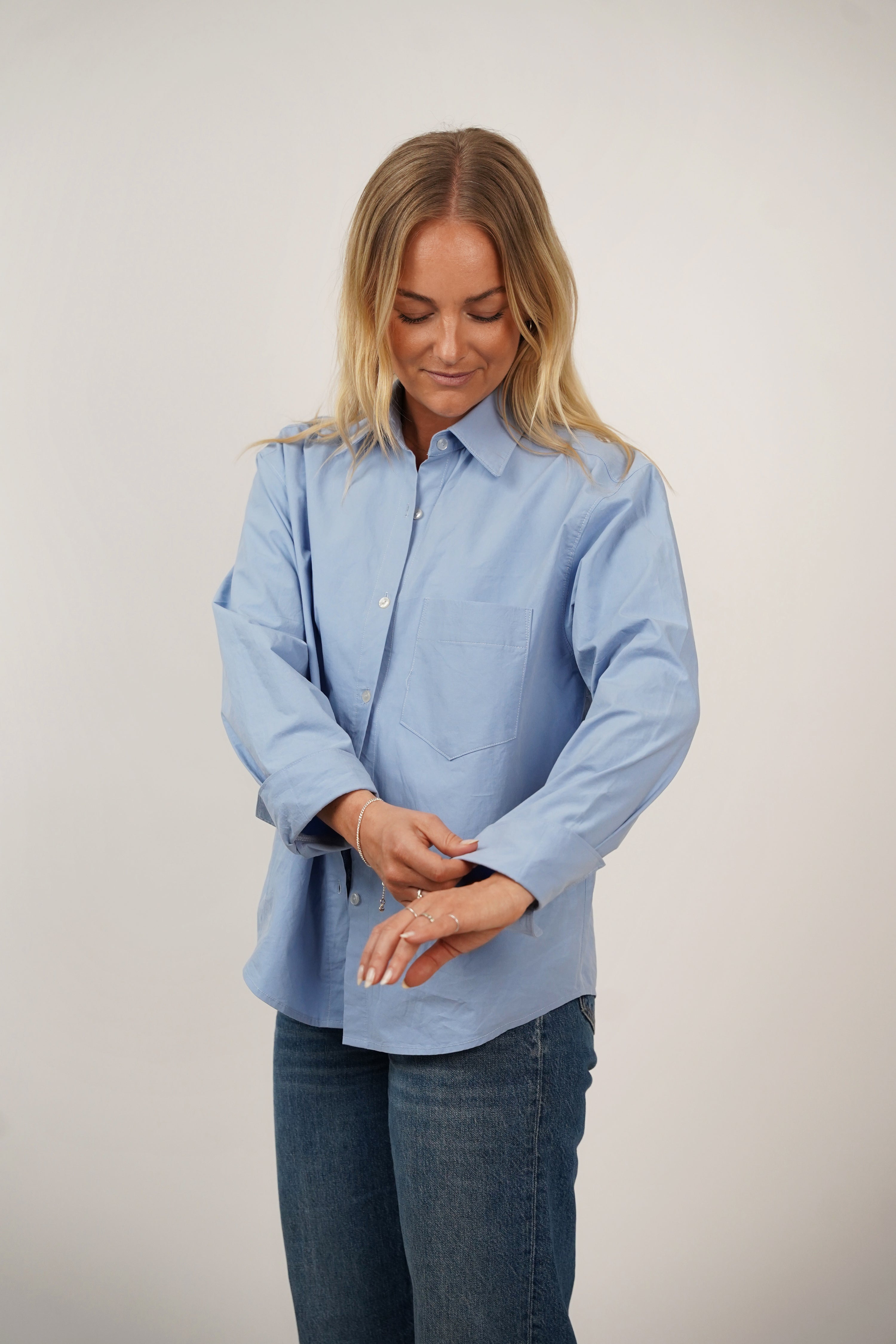 Woman wearing the Boxy Shirt sewing pattern from Wardrobe by Me on The Fold Line. A shirt pattern made in cotton voile, linen, poplin, or chambray fabric, featuring an oversized fit, shirt collar, dropped shoulder, long sleeves with cuffs, and chest pocket.