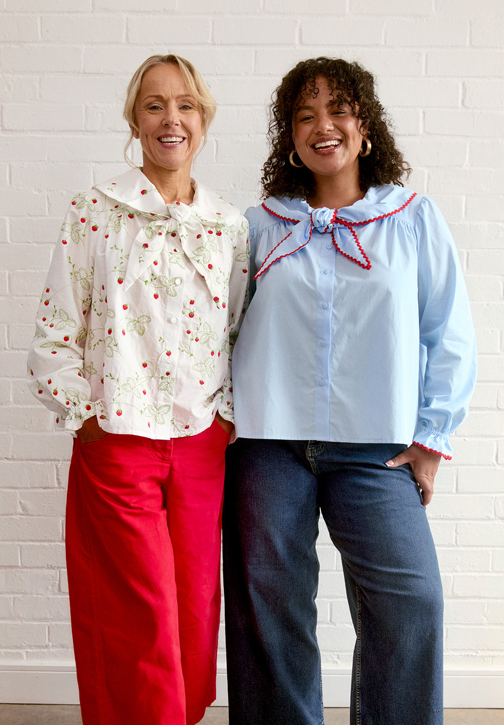 Women wearing the Bramble Blouse sewing pattern from Fabric Godmother on The Fold Line. A top pattern made in cotton, linen, corduroy, chambray, or lightweight denim fabric, featuring a relaxed A-line silhouette, scarf-like tie collar, gathers at the yoke, long puff sleeves, and elasticated ruffle cuffs.