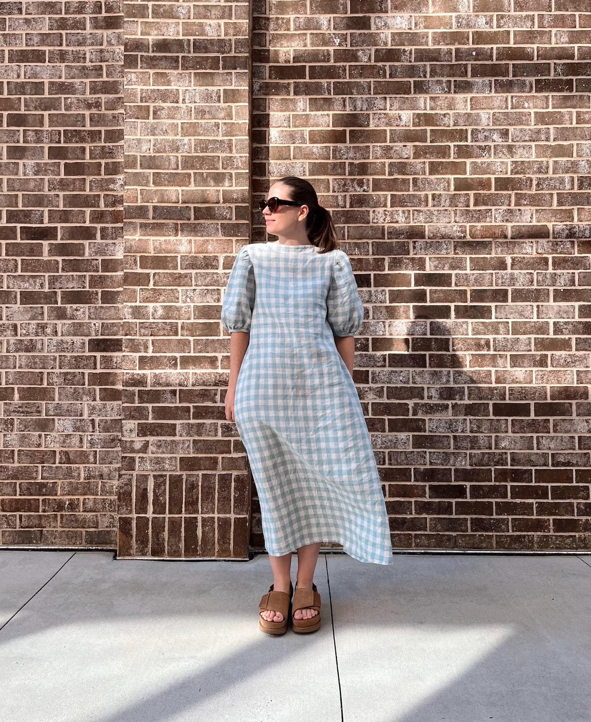 Woman wearing the Bree Dress sewing pattern from Me & Kiddo Patterns on The Fold Line. A dress pattern made in cotton, linen, or rayon/viscose fabric, featuring a slim A-line fit, round neckline, elbow-length puff sleeves, and midi/maxi length.