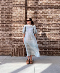Woman wearing the Bree Dress sewing pattern from Me & Kiddo Patterns on The Fold Line. A dress pattern made in cotton, linen, or rayon/viscose fabric, featuring a slim A-line fit, round neckline, elbow-length puff sleeves, and midi/maxi length.