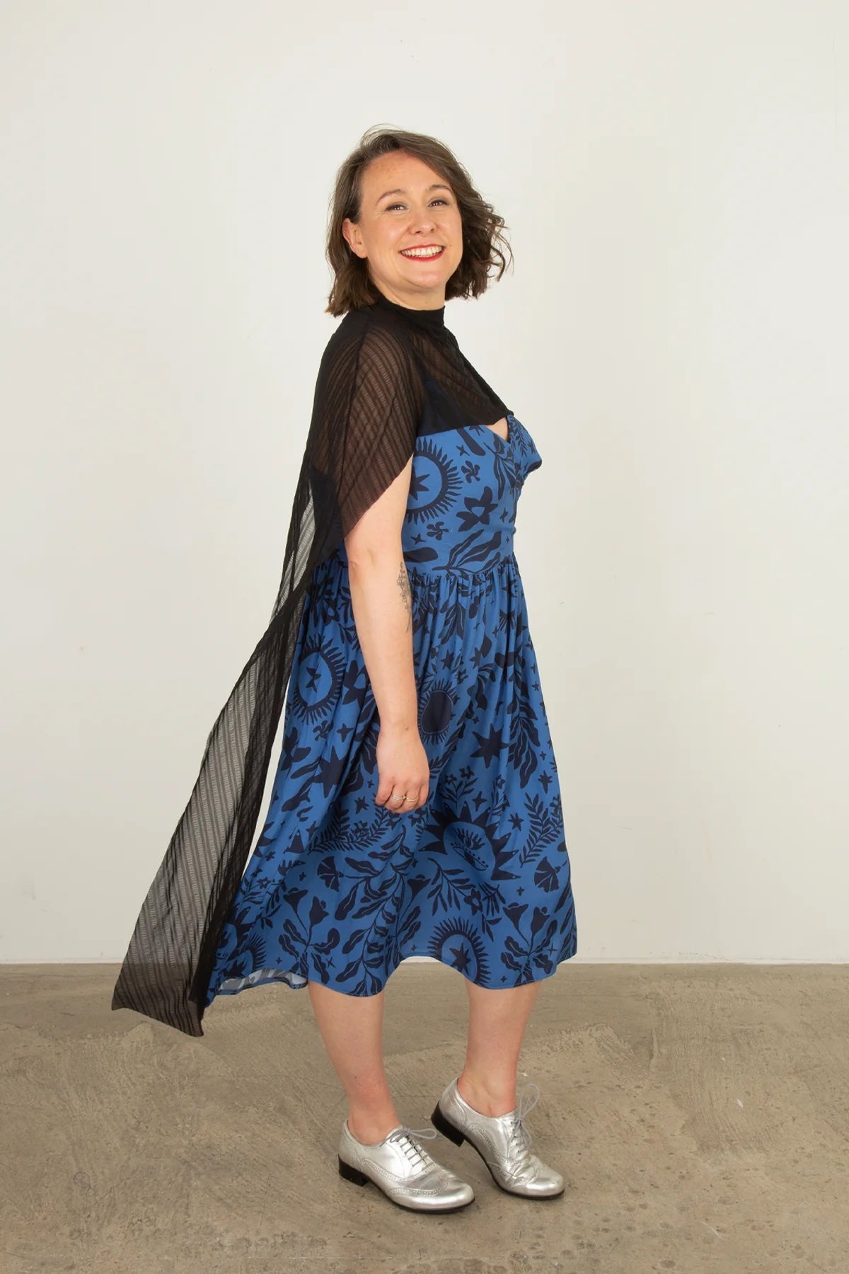 Woman wearing the Bronte Cape sewing pattern from Sew Over It on The Fold Line. A cape pattern made in knit or mesh fabric, featuring a cowl neckline and long flowing panels.