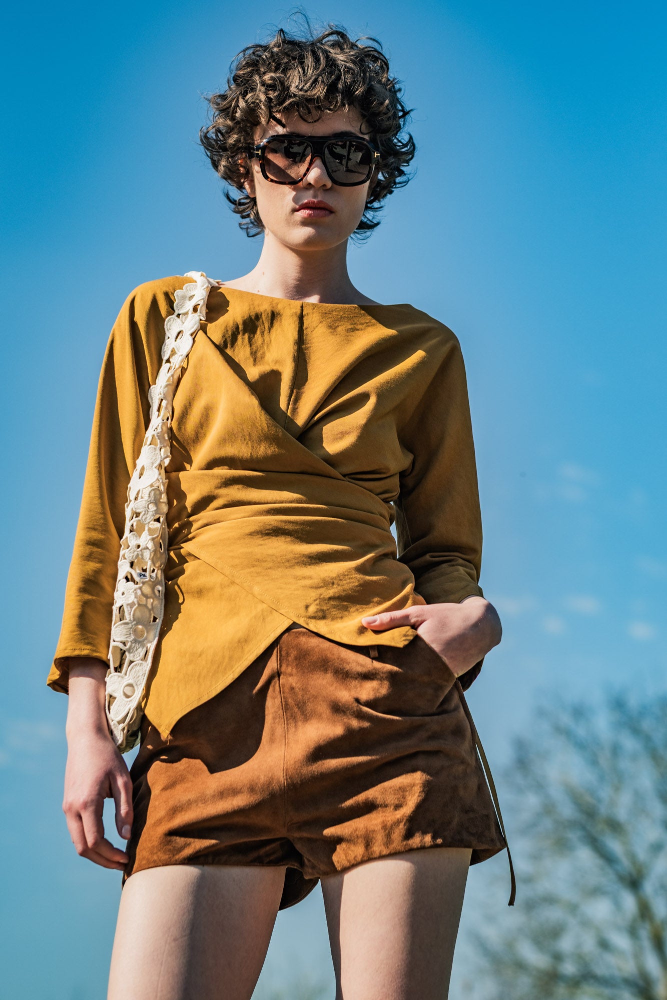 Woman wearing the Bryn Top sewing pattern from Fibre Mood on The Fold Line. A wrap top pattern made in crepe, lyocell, cupro, satin, linen, viscose, cotton, seersucker, fine corduroy, or chambray fabric, featuring an asymmetrical silhouette, boat neck, and three-quarter sleeves.