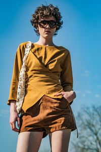 Woman wearing the Bryn Top sewing pattern from Fibre Mood on The Fold Line. A wrap top pattern made in crepe, lyocell, cupro, satin, linen, viscose, cotton, seersucker, fine corduroy, or chambray fabric, featuring an asymmetrical silhouette, boat neck, and three-quarter sleeves.