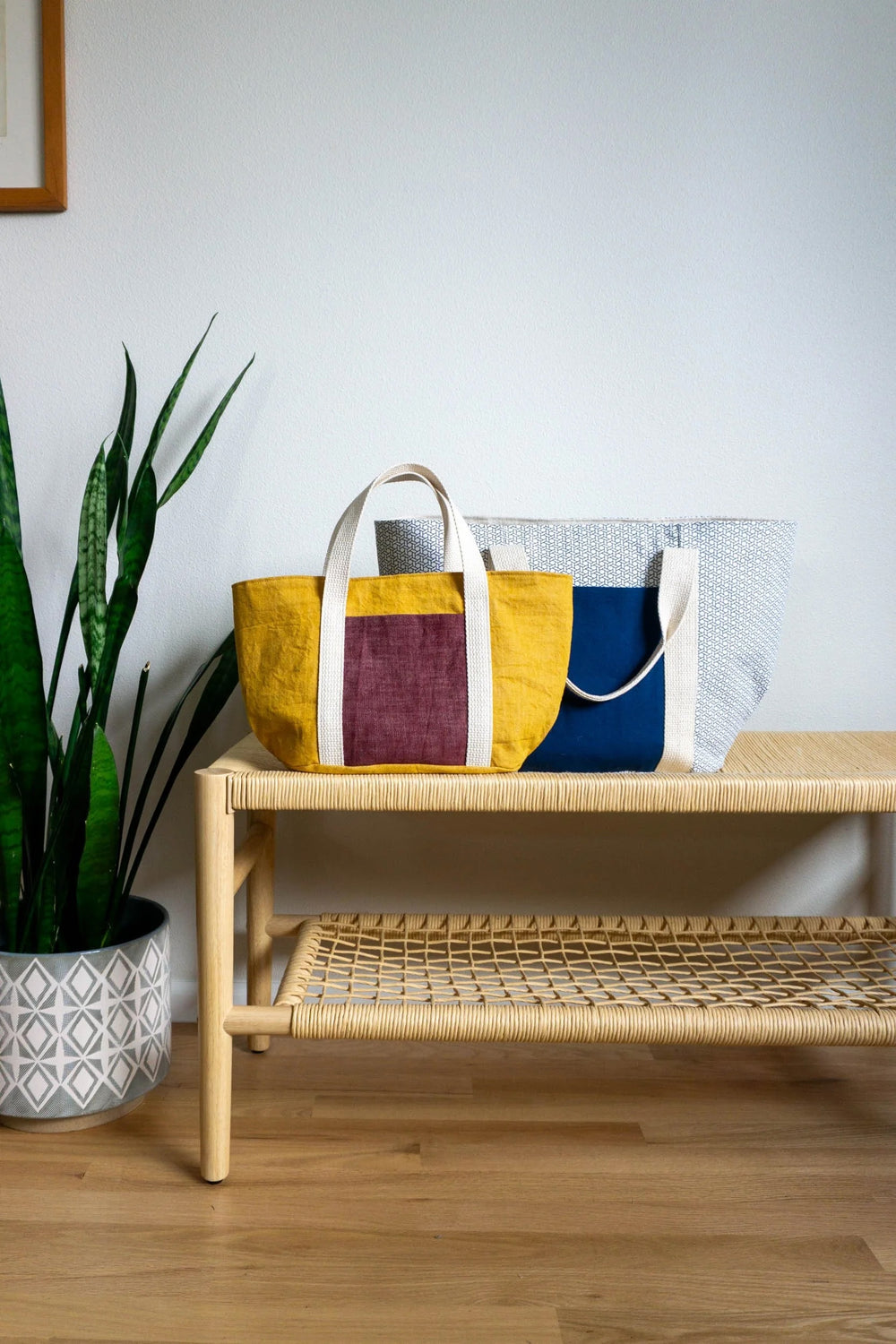 The Bucket Tote sewing pattern from Sew DIY on The Fold Line. A tote bag pattern made in canvas, denim, or corduroy fabric, featuring a full lining, oval base, exterior and interior pockets, webbing handles, and two sizes.