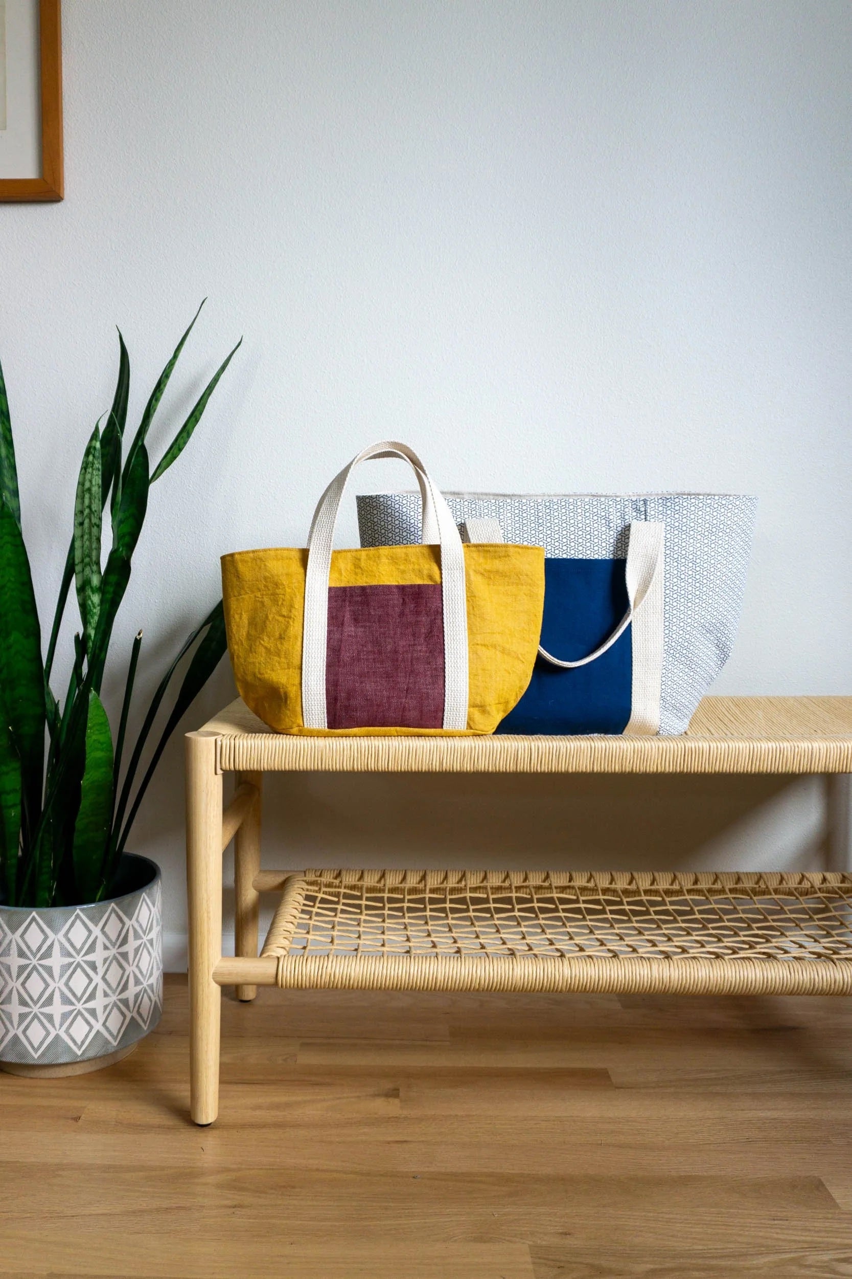 The Bucket Tote sewing pattern from Sew DIY on The Fold Line. A tote bag pattern made in canvas, denim, or corduroy fabric, featuring a full lining, oval base, exterior and interior pockets, webbing handles, and two sizes.
