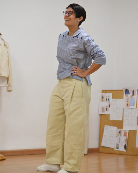Woman wearing the Calig Trousers sewing pattern from Pauline Alice on The Fold Line. A trousers pattern made in poplin, linen, denim, gabardine, corduroy, or lightweight wool fabric, featuring a relaxed fit, curved silhouette, waist facing, zip fly, front pleats, side pockets, back welt pocket, and topstitching.