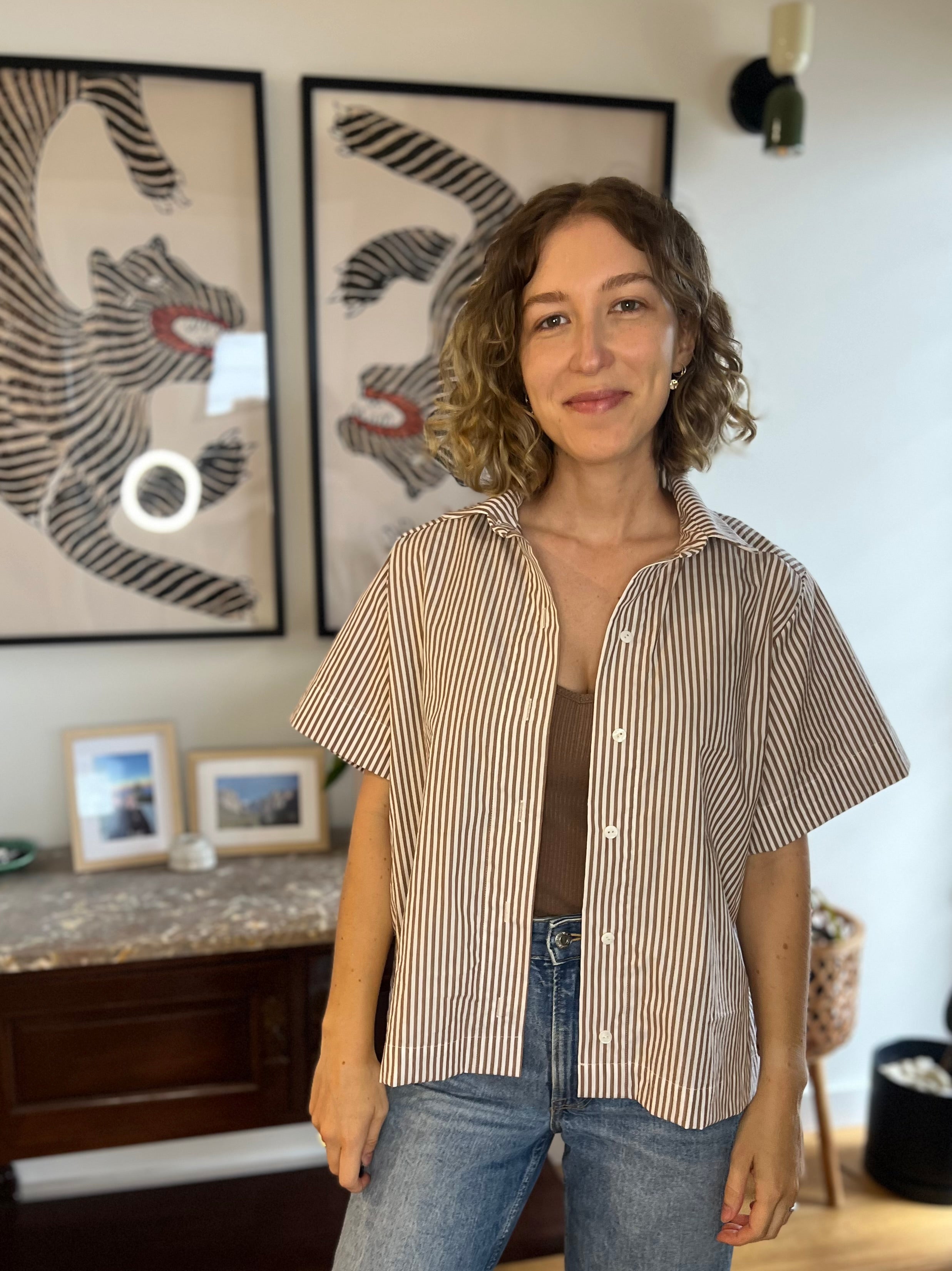 Woman wearing the Calla Shirt sewing pattern from Elle Stitch on The Fold Line. A shirt pattern made in cotton shirting, lightweight linen, or rayon linen blend fabric, featuring an oversized fit, collar and collar stand, button front, short sleeves, back yoke, and gathers along the back.