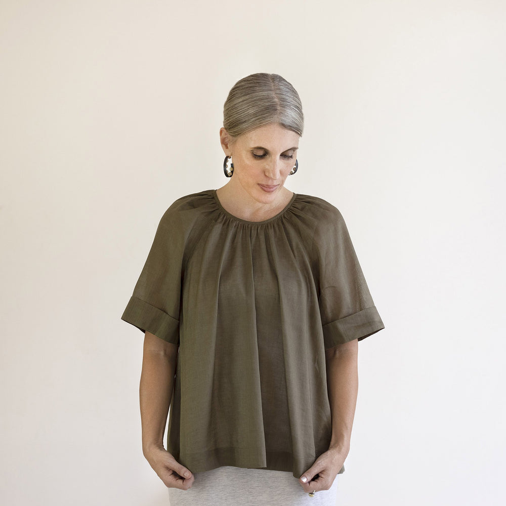 Woman wearing the Calyx Smock sewing pattern from Pattern Fantastique on The Fold Line. A top pattern made in woven fabrics, featuring a relaxed fit, round gathered neckline, and elbow length sleeves.