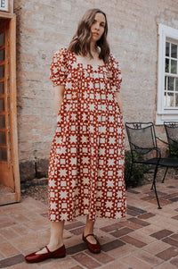 Woman wearing the Camille Chemise sewing pattern from Madswick on The Fold Line. A dress pattern made in Indian block print, woven cotton, linen, linen/rayon blend, or cotton seersucker fabric, featuring a relaxed fit, square neckline, short puff sleeves, box pleats, in-seam pockets, and midi length.