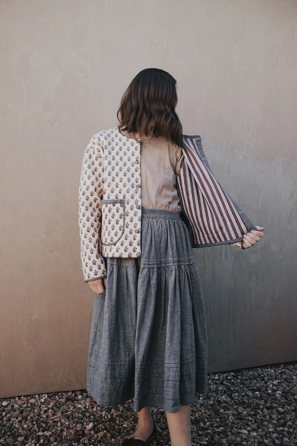 Woman wearing the Capella Coat sewing pattern from Madswick on The Fold Line. A quilted jacket pattern made in cotton, linen, or pre-quilted fabric, featuring a boxy fit, slight drop shoulder, button front, elasticated back hem, patch pockets, bias-bound seams, and reversible design.