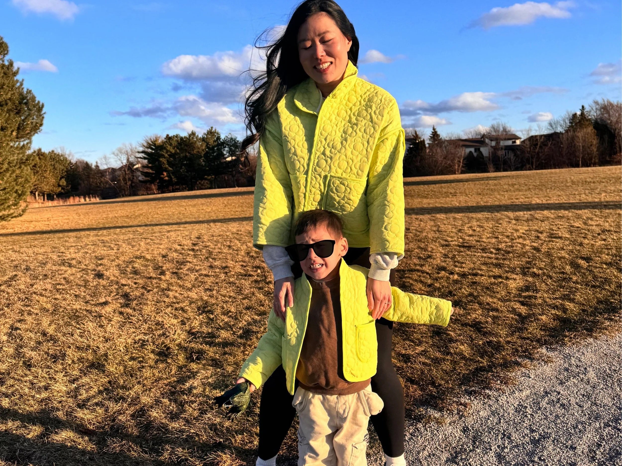 Woman and boy wearing the Cardamom Quilt Jacket sewing pattern from Sew Bake Make on The Fold Line. A jacket pattern made in a lightweight thrifted quilt or quilted fabric, featuring a roomy fit, stand collar, and pockets.