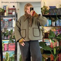 Woman wearing the Cardamom Quilt Jacket sewing pattern from Sew Bake Make on The Fold Line. A jacket pattern made in a lightweight thrifted quilt or quilted fabric, featuring an oversized fit, stand collar, snap closures, and patch pockets.
