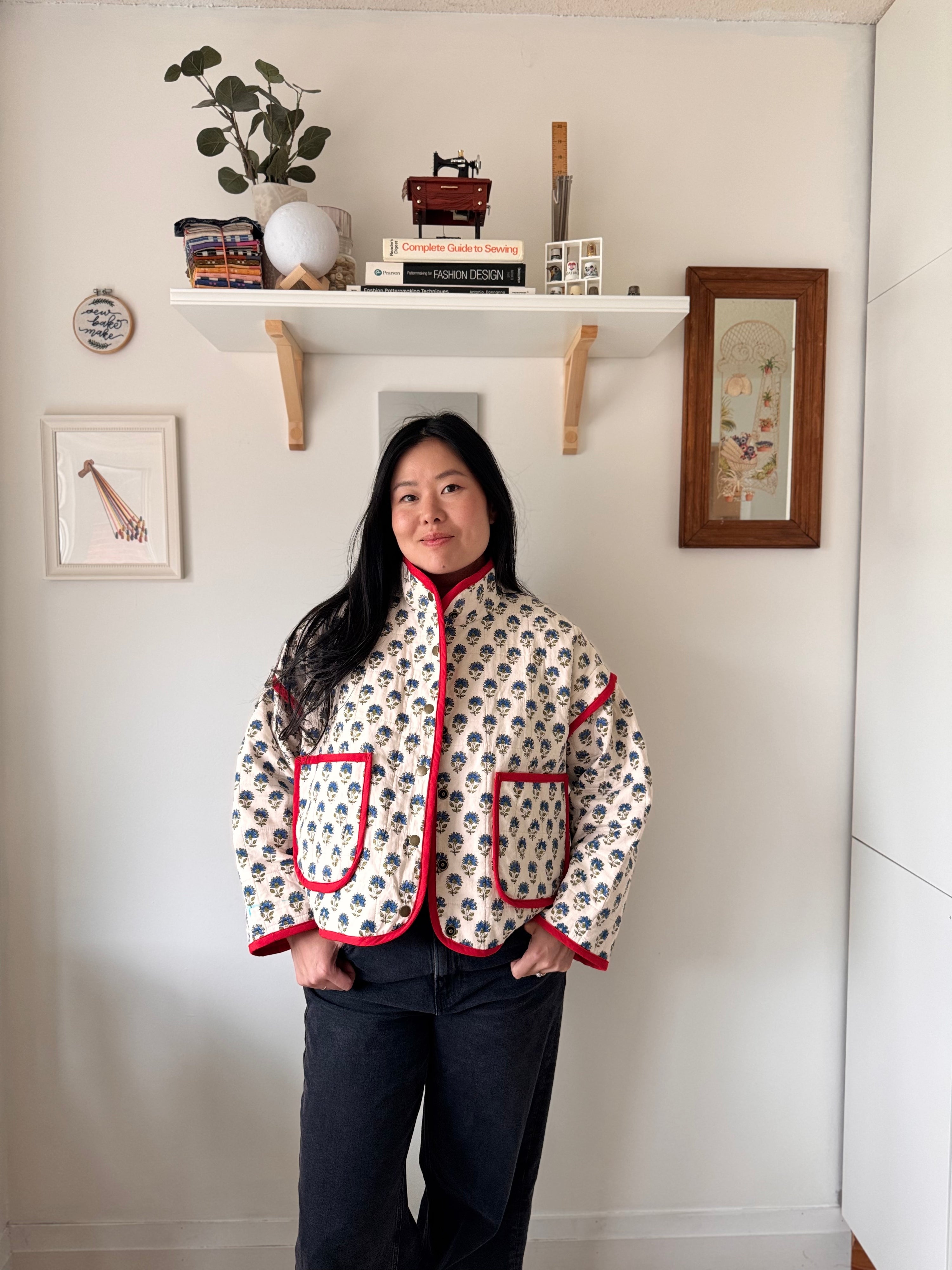 Woman wearing the Cardamom Quilt Jacket sewing pattern from Sew Bake Make on The Fold Line. A jacket pattern made in a lightweight thrifted quilt or quilted fabric, featuring an oversized fit, stand collar, snap closures, and patch pockets.