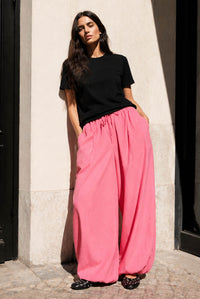 Woman wearing the Carly Balloon Pants sewing pattern from JULIANA MARTEJEVS on The Fold Line. A trousers pattern made in cotton poplin, viscose, tencel, or linen fabric, featuring an elasticated waistband with a drawstring, side seam pockets, and wide legs with elasticated hems.