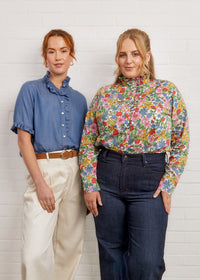 Women wearing the Carnation Blouse sewing pattern from Fabric Godmother on The Fold Line. A shirt pattern made in viscose, cotton lawn, cotton poplin, or silk fabric, featuring a narrow collar with a ruffle, button front, and short sleeves with a ruffle or long sleeves with a cuff.