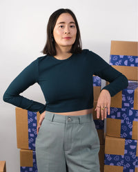Woman wearing the Carrie Crop Top sewing pattern from BF Patterns on The Fold Line. A fitted T-shirt pattern made in knit fabric, featuring a round neckline, long sleeves, and cropped length.