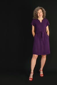 Woman wearing the Chacarita Wrap Dress sewing pattern from Liesl + Co on The Fold Line. A dress pattern made in linen, rayon, or soft cotton fabric, featuring a bias-cut top with a notch at the front neck, short sleeves, ties at the front waist, on-seam pockets, a V-neck at the back, and knee length.