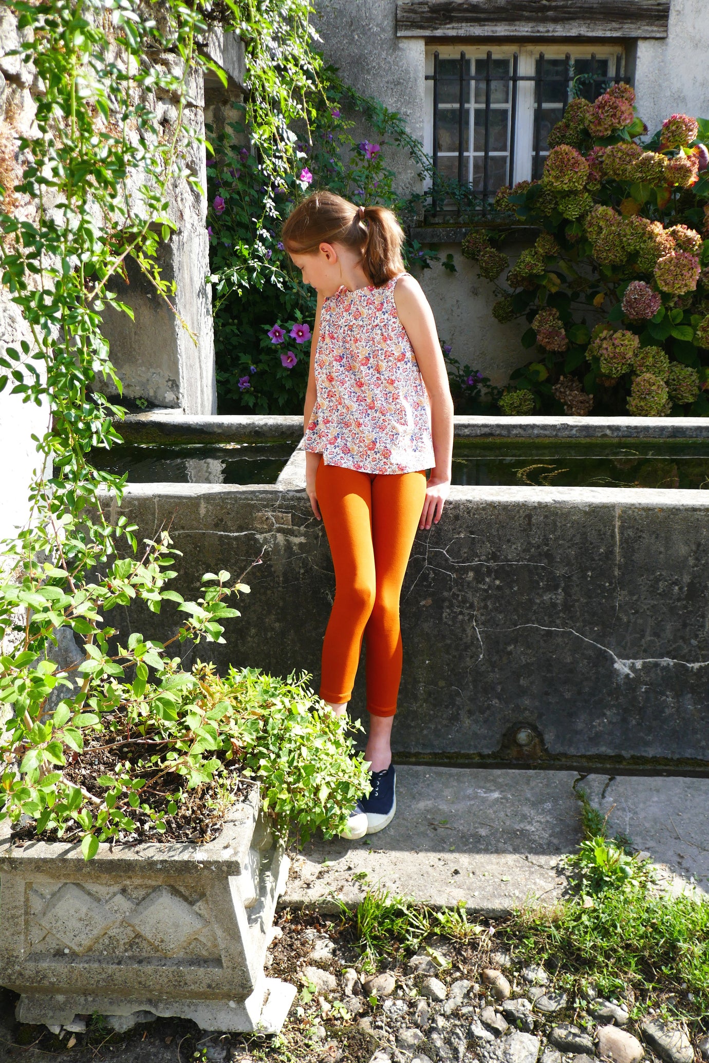 Girl wearing the Child/Teen Bodega Leggings sewing pattern from Petits D'om on The Fold Line. A leggings pattern made in 4-way stretch jersey fabric, featuring a close fit and long leg.